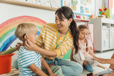 teacher helping child with hearing aids
